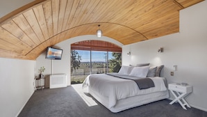 A bedroom with a large bed, a TV, a bedside table, and a view of the outdoors. - Panoramic mountain and rural views - central to key destinations
 (Te Awamutu)