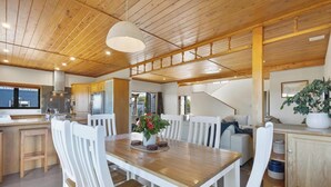 A modern kitchen with wooden cabinets, a dining area with a wooden table and white chairs, and a staircase leading to an upper level. - Panoramic mountain and rural views - central to key destinations
 (Te Awamutu)