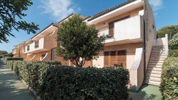 Una hilera de edificios de dos pisos con balcones, un árbol en el centro y un cielo despejado.