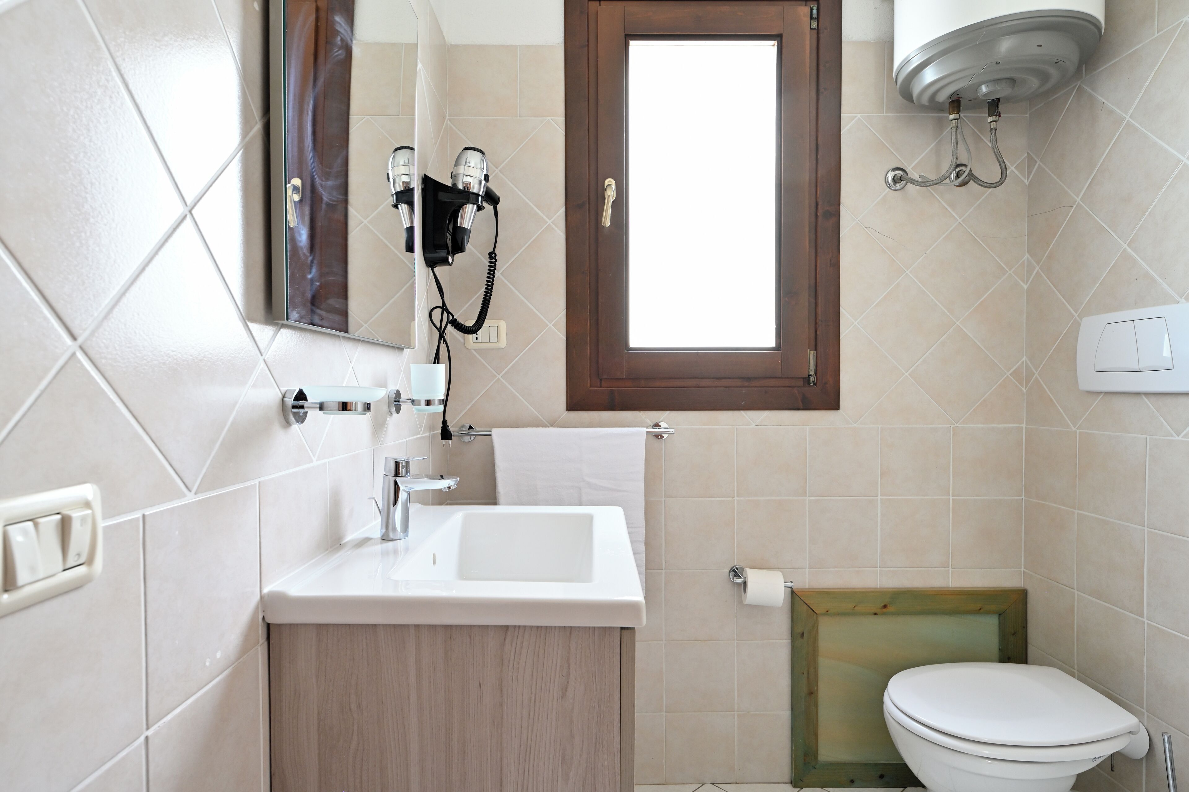 Un baño con lavamanos, espejo, secador de pelo e inodoro.