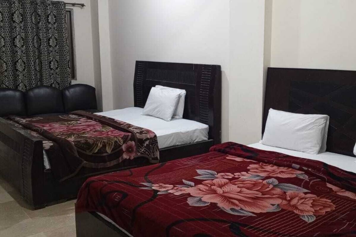 Een kamer met twee bedden, elk met een ander hoofdeinde. Er staat een klein tafeltje met een stoel voor een van de bedden.