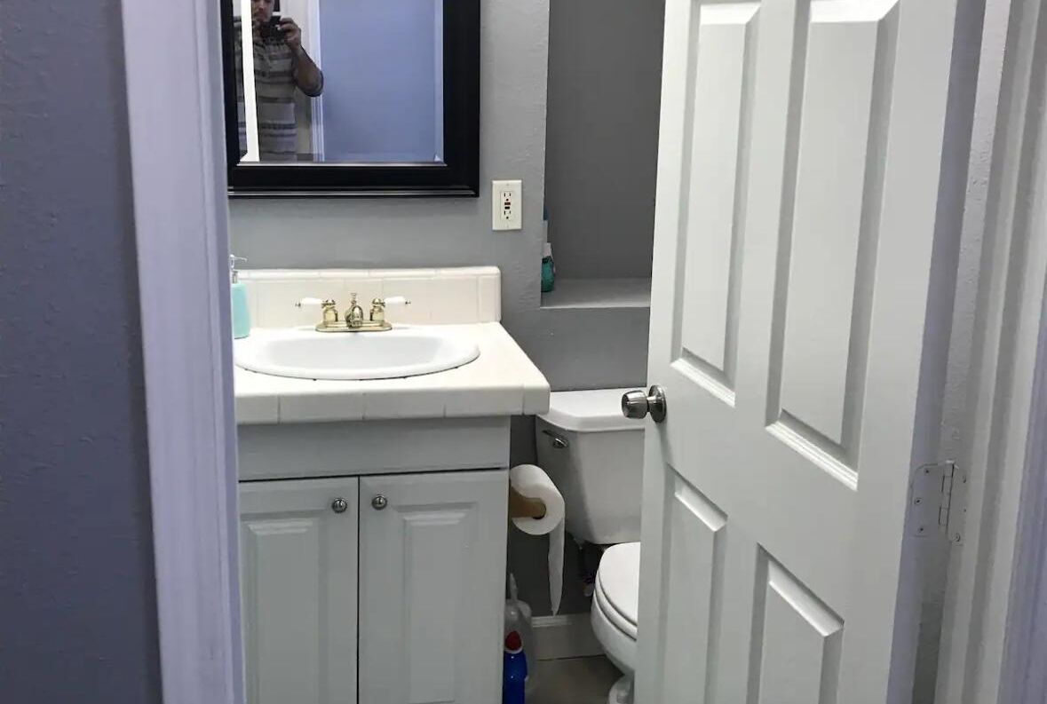 A small bathroom with a white sink, toilet, and a mirror above the sink.