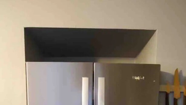 A stainless steel refrigerator with two doors and a freezer drawer, located in a kitchen with wooden flooring and white cabinets. - Desert Casita Guesthouse (Joshua Tree)