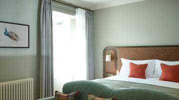 Una habitación de hotel con una cama grande, un sofá verde y un cuadro de un pavo real en la pared.