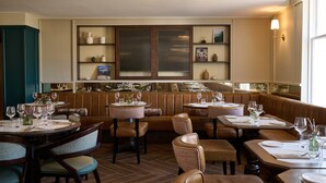 Un restaurant avec des banquettes et des tables, un plancher en bois et un mur décoratif agrémenté d’étagères.