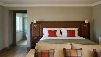Une chambre d’hôtel avec un grand lit, deux tables de chevet, une commode, une fenêtre et une porte donnant sur une salle de bain.