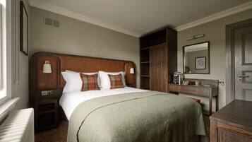 Quarto de hotel com uma cama grande, mesa de cabeceira, cômoda, espelho e radiador.