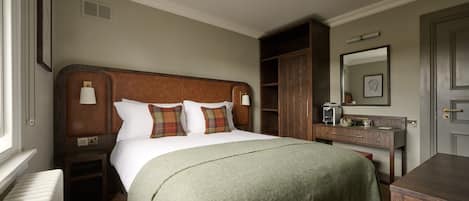 A hotel room with a large bed, a nightstand, a dresser, a mirror, and a radiator.