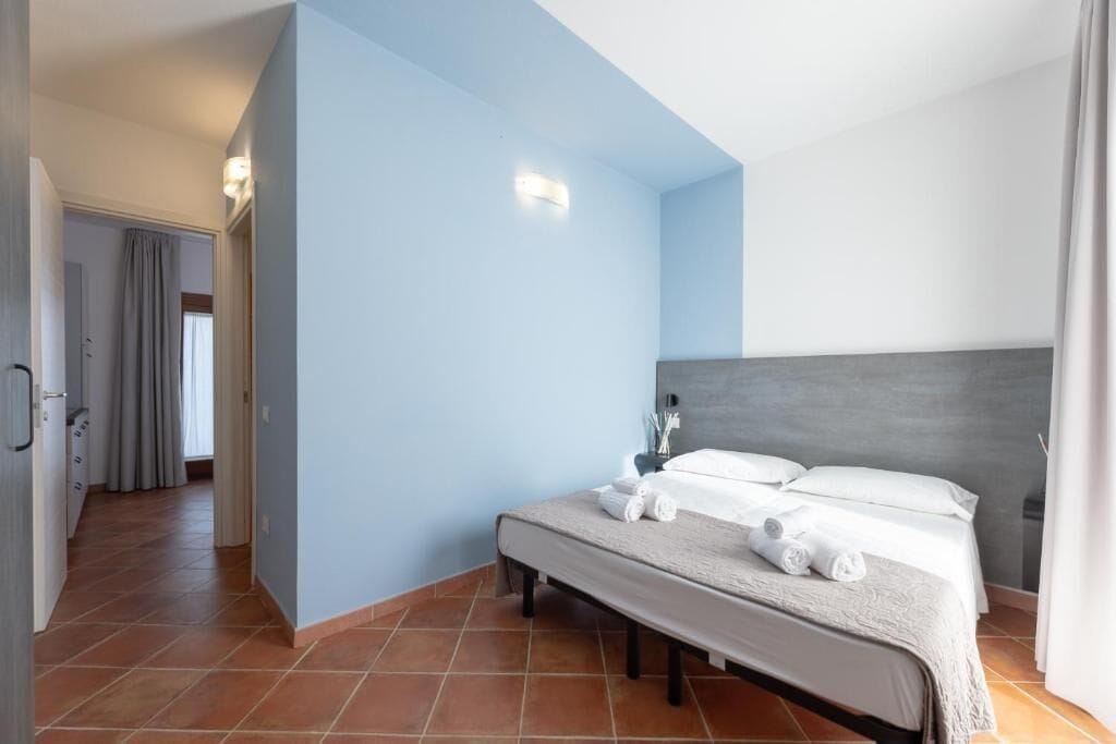 A hotel room with a bed, a nightstand, and a bathroom visible in the background.