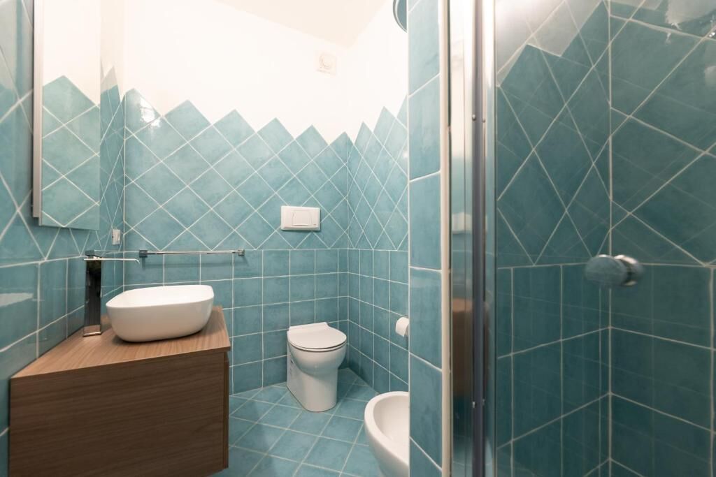 A bathroom with a modern design, featuring a large mirror, a sink, a toilet, and a shower area.
