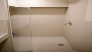Ein kleines, gefliestes Duschbad mit einer Duschbrause und Ablauf.