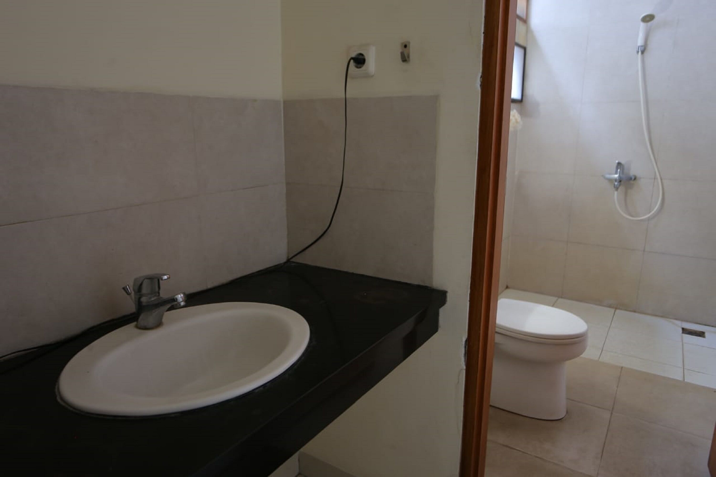 A bathroom with a white sink, black countertop, and a toilet.