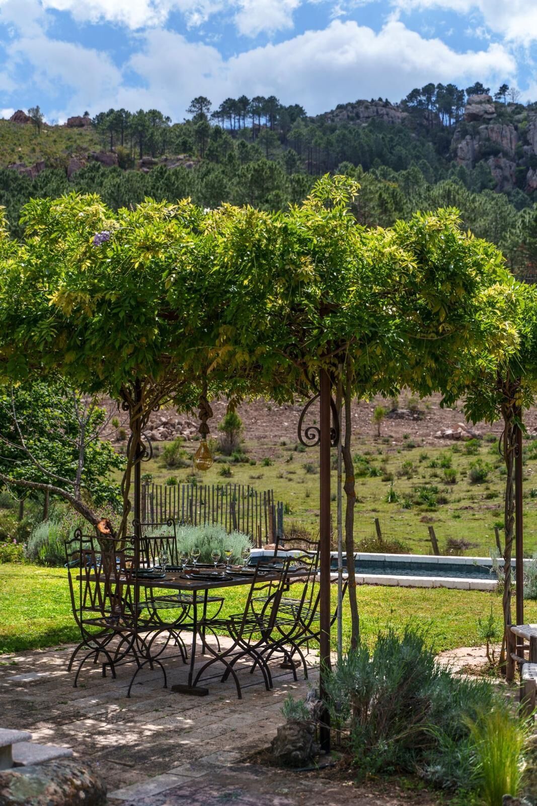 Uma área de refeições ao ar livre com pérgola, mesas e cadeiras.