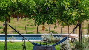 Une terrasse avec une table et des chaises, un hamac et une vue sur une montagne et une étendue d’eau.