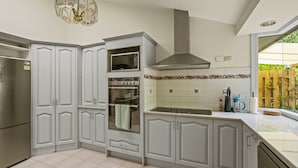 A kitchen with white cabinets, a built-in oven, a microwave, and a stainless steel range hood. - StayAU 4BR Spacious Nature Retreat (Badger Creek)