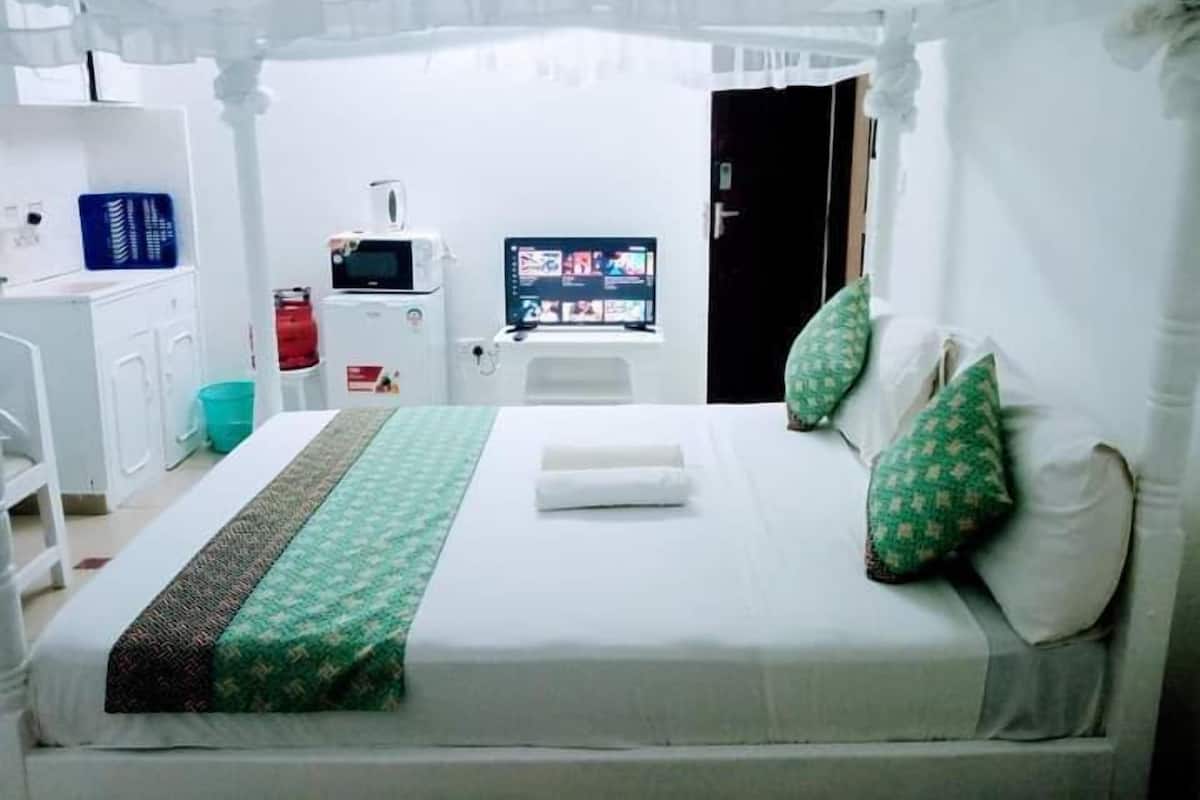 Una habitación de hotel con cama, escritorio, televisión y baño.