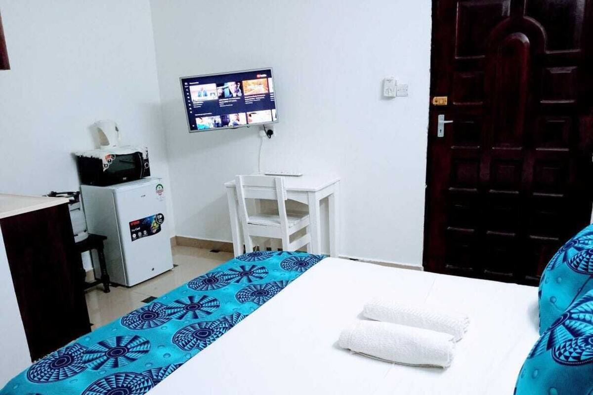 Habitación de hotel con cama, escritorio, computadora, televisión y microondas.