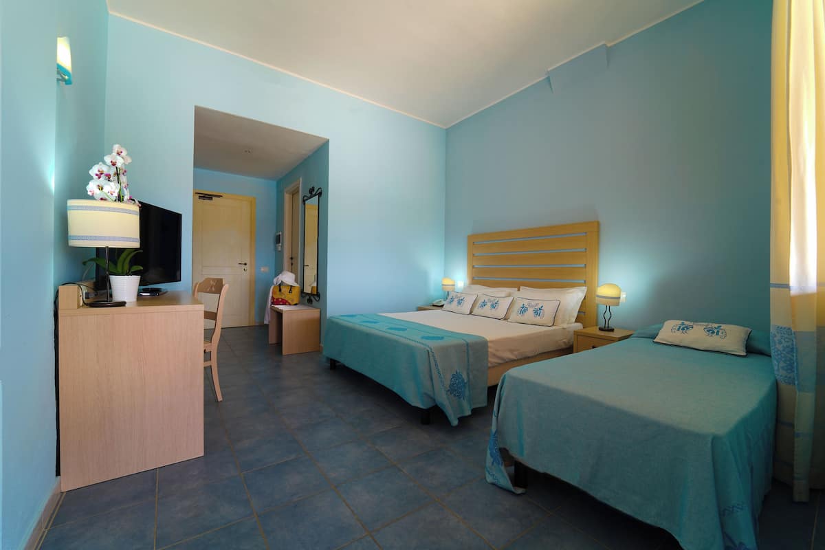 Een hotelkamer met twee bedden, een bureau, een stoel en een televisie.
