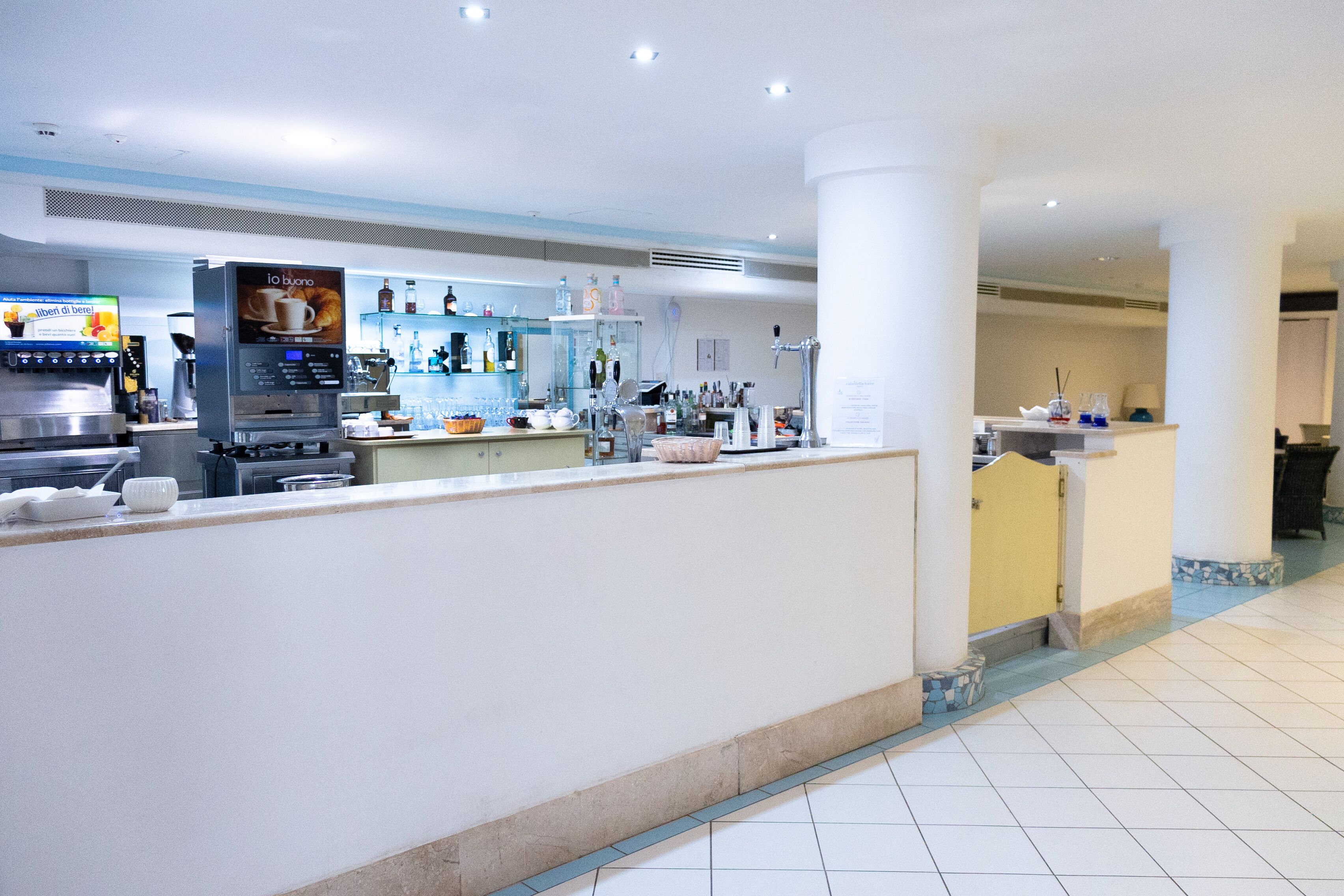 Un moderno vestíbulo de hotel con una máquina de café, una recepción y una zona de bar.