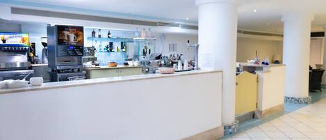 Un moderno vestíbulo de hotel con una máquina de café, una recepción y una zona de bar.