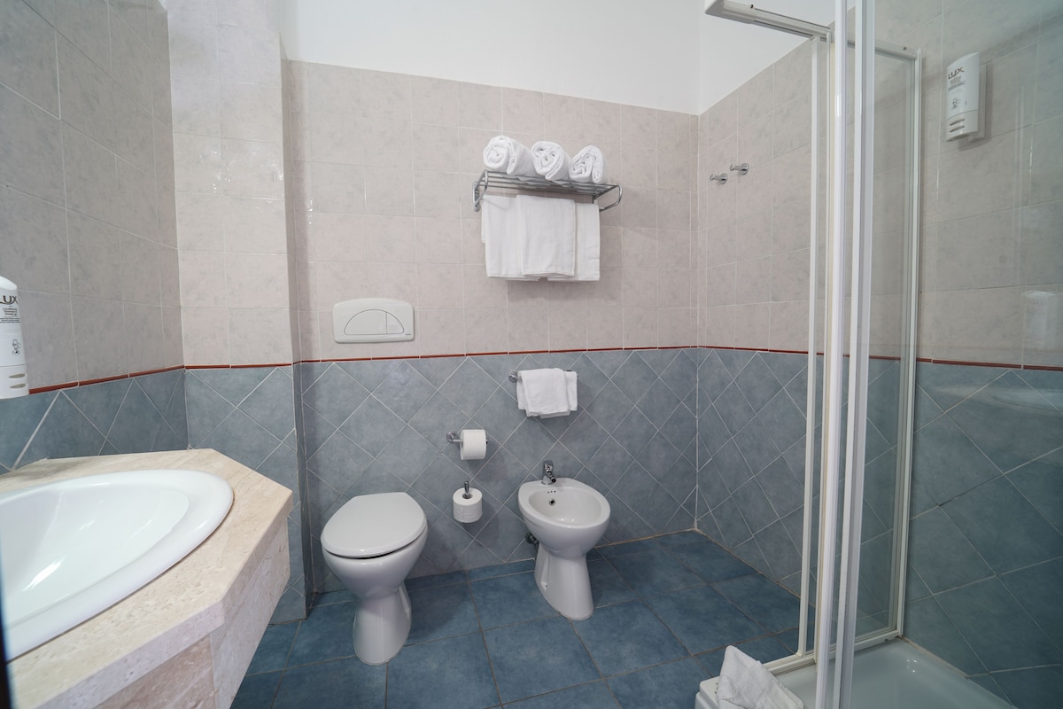 A bathroom with a bathtub, toilet, bidet, and a glass-enclosed shower.
