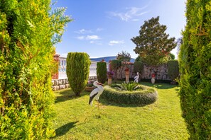 A well-maintained garden with a stork, neatly trimmed hedges, and a stone wall. - Seafront Haven Darka Beach & Garden (Bijela)
