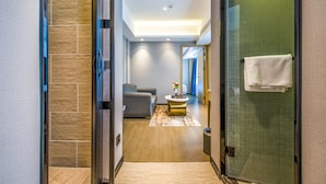 A modern hotel hallway with a glass door, a grey sofa, a round coffee table, and a mirror. - Meihao Hotel Shenzhen Sungang Branch (Shenzhen)