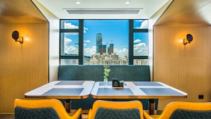 A modern dining area with a city view, featuring a table with two chairs, a vase with flowers, and a menu stand. - Meihao Hotel Shenzhen Sungang Branch (Shenzhen)