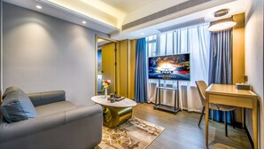 A modern living room with a sofa, coffee table, TV, and a dining area. - Meihao Hotel Shenzhen Sungang Branch (Shenzhen)