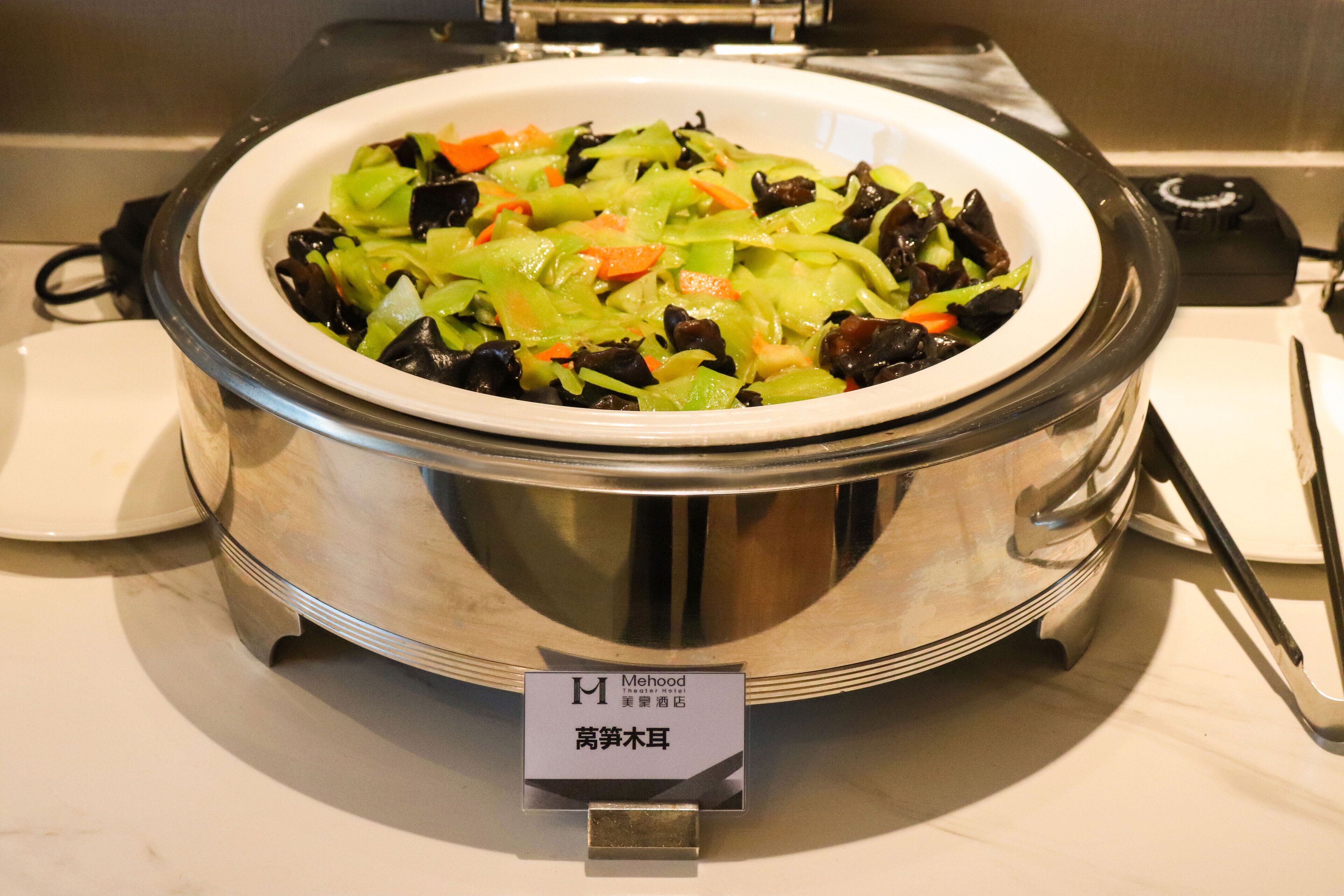 A large metal bowl filled with vegetables on a marble countertop.