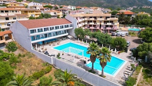 A hotel with a swimming pool, multiple floors, and a view of the surrounding town and hills. - Horizon Hotel Badesi (Badesi)