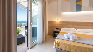 A hotel room with a bed, a nightstand, a potted plant, and a view of the sea through a sliding door. - Horizon Hotel Badesi (Badesi)