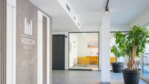 A modern hotel lobby with a reception desk, a large potted plant, and a view of the interior. - Horizon Hotel Badesi (Badesi)