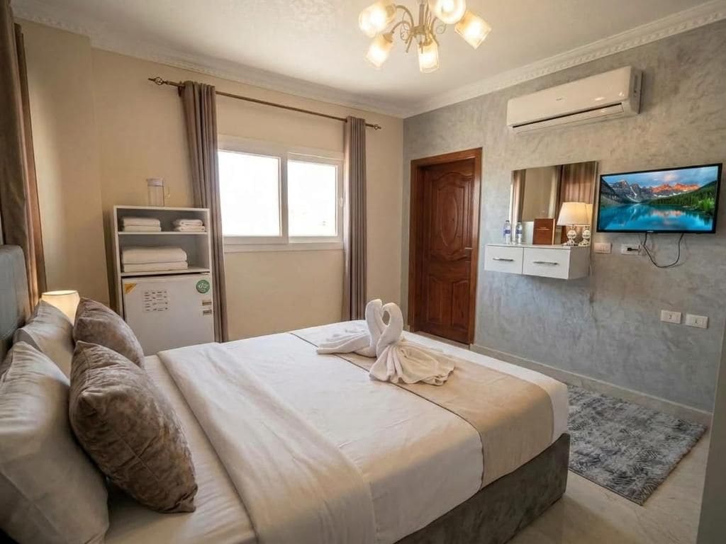 Une chambre d’hôtel avec un lit, une télévision, une armoire et une fenêtre avec des rideaux.
