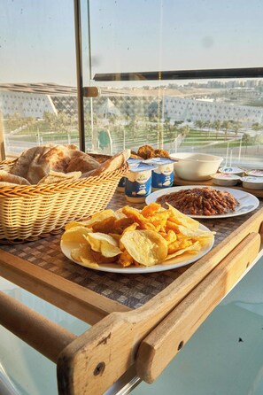 A table with a basket of bread, bowls of dips, chips, and a plate of beans. - GEM VIEW INN (Giza)