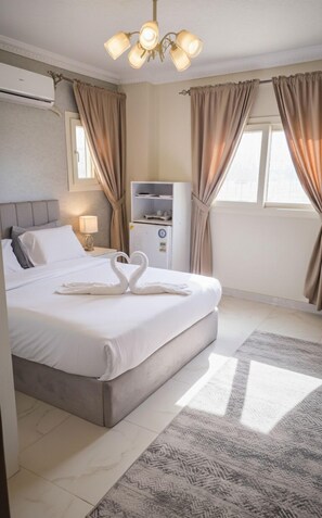 A hotel room with a large bed, a minibar, a ceiling light fixture, and a window with curtains. - GEM VIEW INN (Giza)