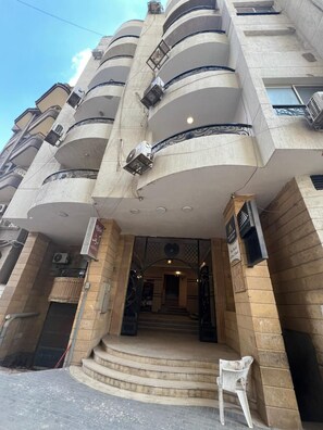 Un edificio de varios pisos con una entrada central, balcones y una escalera que conduce a la entrada.