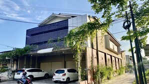 A modern building with a large garage door, parked cars, and a motorcycle on the street. - Hotel O Delia Inn Syariah (Klaten)