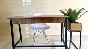 A modern table with a wooden top and black metal frame, accompanied by a white chair and a potted fern. - Hotel O Delia Inn Syariah (Klaten)