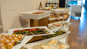 Un bufé con una variedad de platos, incluyendo ensaladas, pasta y postres.