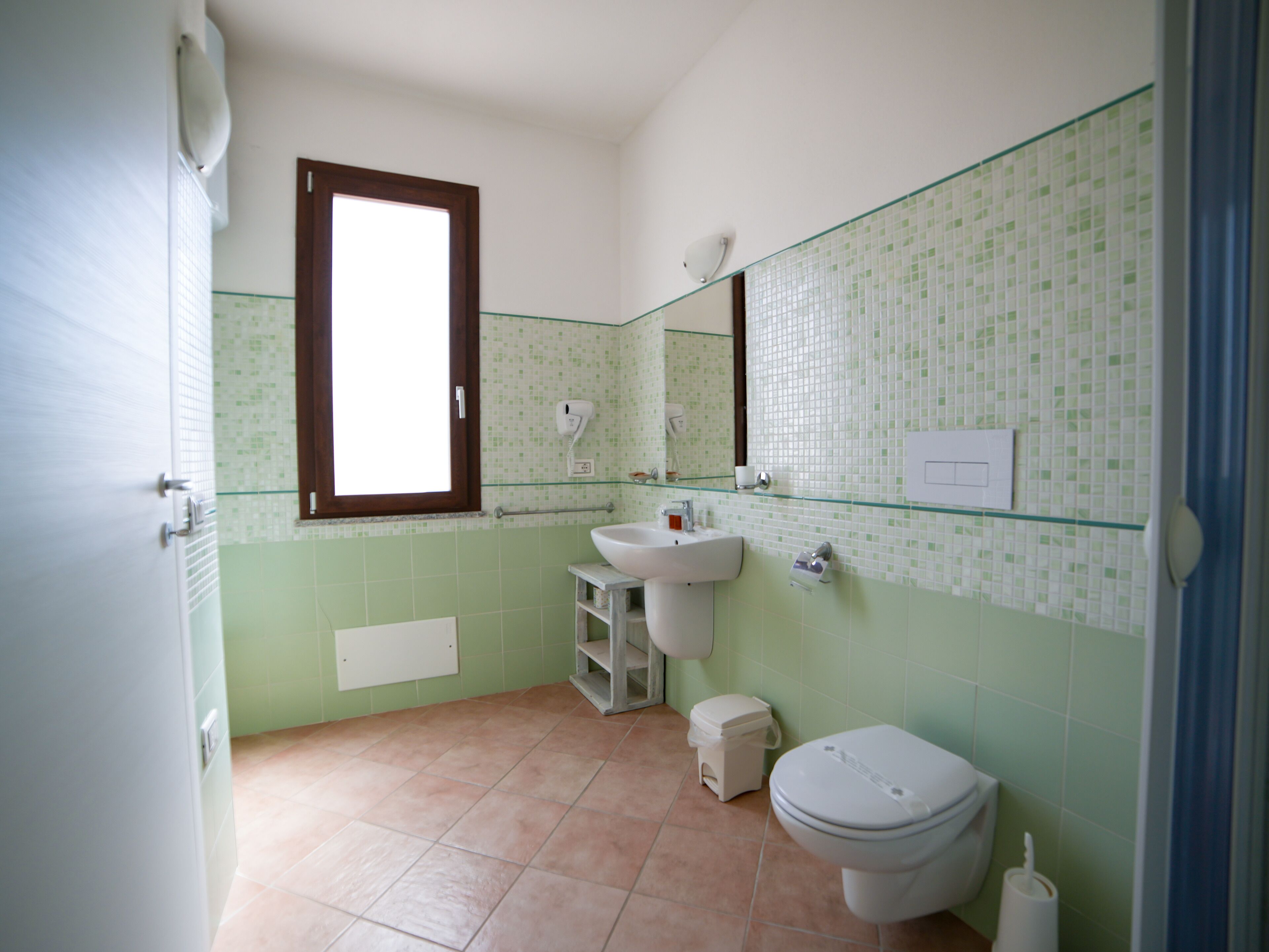 Ein Badezimmer mit Toilette, Waschbecken und Fenster.