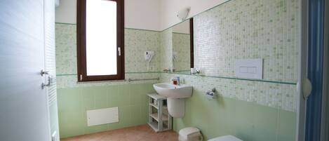Ein Badezimmer mit Toilette, Waschbecken und Fenster.