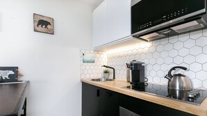 Una cocina moderna con encimera de madera, electrodomésticos de acero inoxidable y un salpicadero de azulejos hexagonales.