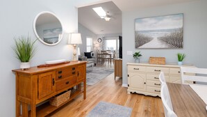 A well-lit room with a wooden dining table, a white bench, a wooden cabinet, and a large painting on the wall. - "Sun Catcher" -Oceanfront Views | Balcony (North Topsail Beach)