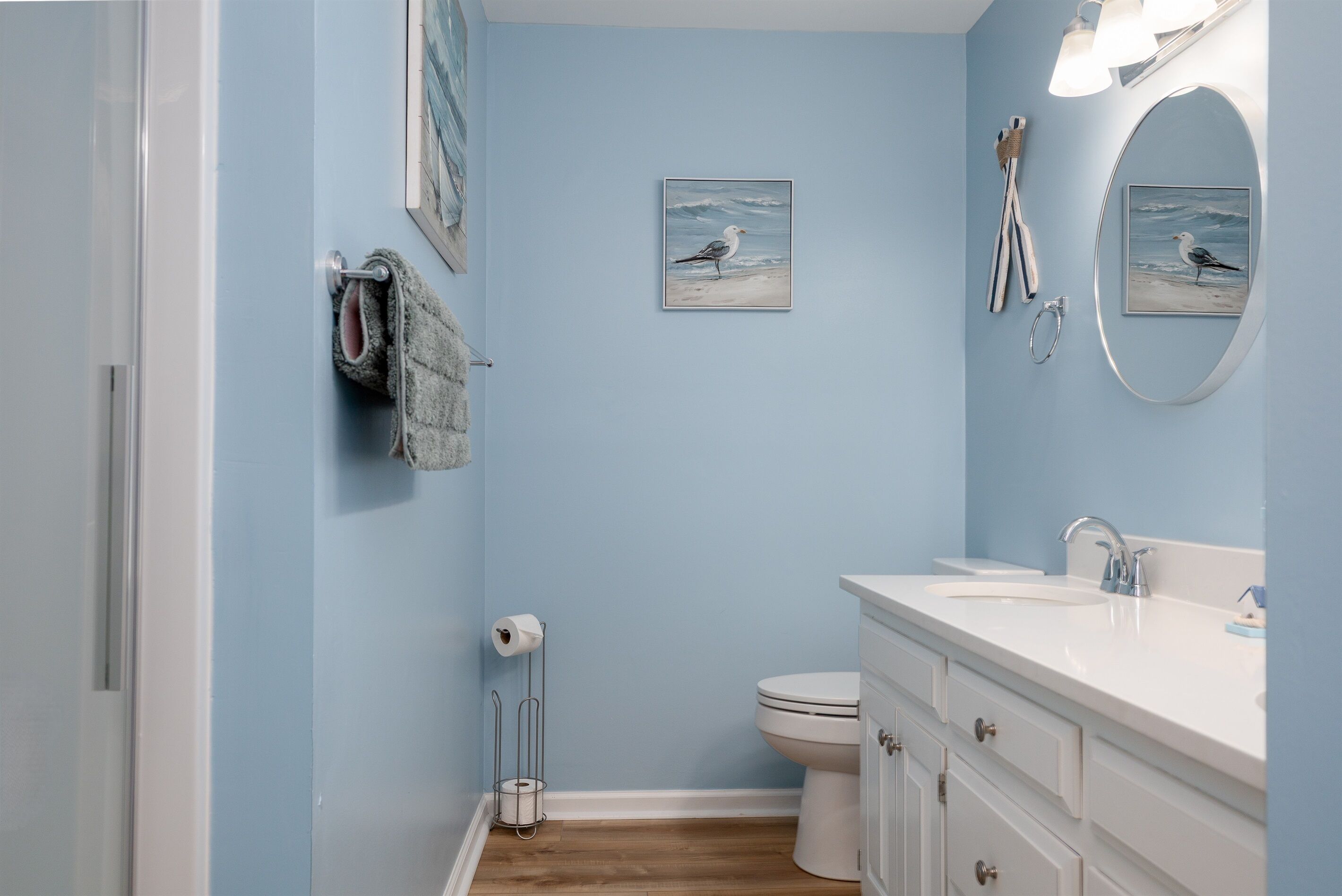 A bathroom with a light blue wall, a white sink, a toilet, and a towel rack.