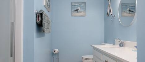 Une salle de bain avec un mur bleu clair, un lavabo blanc, des toilettes et un porte-serviettes.