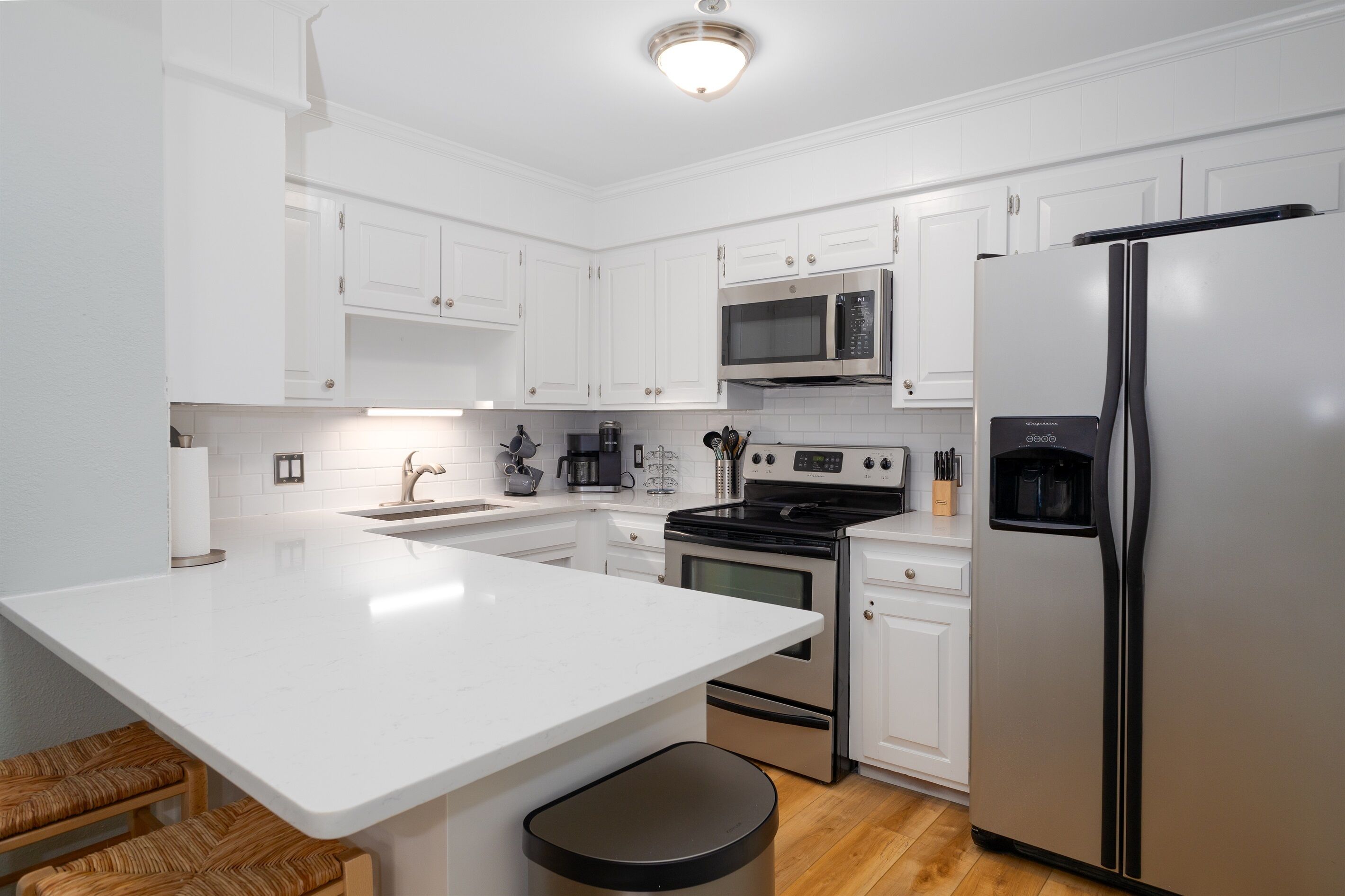 A modern kitchen with white cabinetry, stainless steel appliances, and a central island.