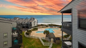 A residential complex with a swimming pool, a view of the ocean, and a sunset sky. - "Sun Catcher" -Oceanfront Views | Balcony (North Topsail Beach)