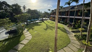 A well-maintained courtyard with a swimming pool, palm trees, and a modern building with balconies.