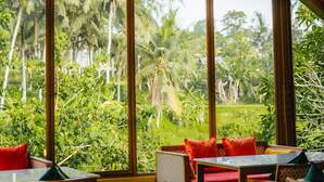 A room with large windows, a colorful stained glass window, and a view of palm trees.